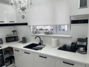 a white kitchen with a sink and a microwave at Apartament Chanel Centrum in Malbork