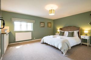 a bedroom with a large bed with green walls at Drift Cottage, Rendlesham in Rendlesham