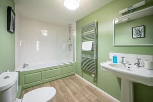 a green bathroom with a toilet and a sink at Drift Cottage, Rendlesham in Rendlesham +54 photos
