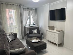 a living room with a couch and chairs and a tv at Apartament Chanel Centrum in Malbork