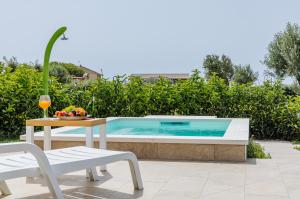ein Pool mit Tisch und Stühlen und ein Tisch mit einem Getränk in der Unterkunft Corallo Home Resort in Le Castella