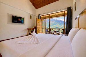 a bedroom with a white bed with a mountain view at Hotel Naina Rockland , Manali in Vashisht