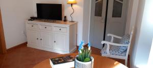 a living room with a table with a television on a cabinet at Casa Dominique in São Pedro do Corval