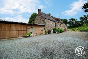 an old stone house with a gravel driveway at Au charme de la forêt in Belle-Isle-en-Terre