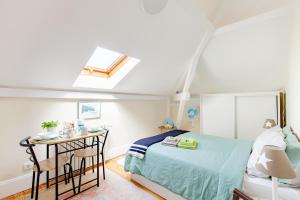 a bedroom with a bed and a table and a skylight at Sky Accommodations family Studios and Suites in Coimbra
