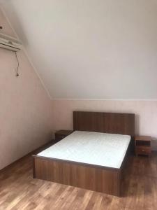 a bedroom with a bed in a room with wooden floors at Море і Сосни in Koblevo