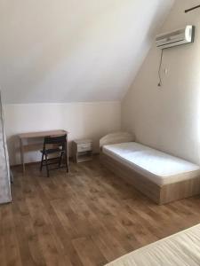 a bedroom with a bed and a desk and a chair at Море і Сосни in Koblevo