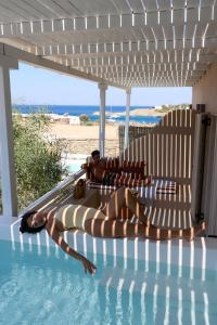 two people laying in the water in a swimming pool at Domotel Kea in Koundouros