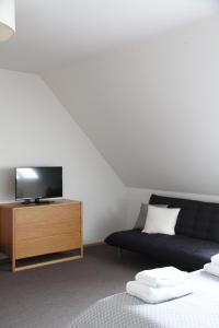 a bedroom with a couch and a tv on a wooden dresser at Neeme Marina Questhouse in Neeme