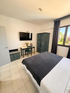 a bedroom with a bed and a table and a television at Traumhaftes Studio mit Meerblick & Pool in Khlorakas