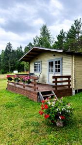 a small house with a deck with flowers in the yard at Rangi Suvemaja in Hiiumaa
