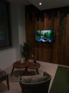 a living room with a table and a tv at Hédoné LoveRooms in La Chapelle
