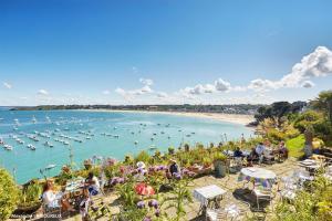 a group of people sitting around a beach with boats in the water at Le sémaphore in Saint-Cast-le-Guildo