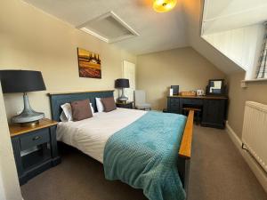 a bedroom with a large bed with a blue blanket at White Hart Hotel in Cricklade