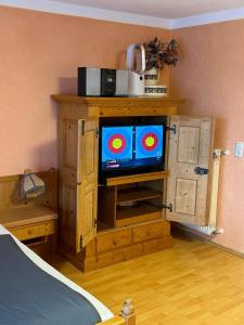 a tv in a wooden cabinet in a bedroom at Haus Hönigsgrub in Rinchnach