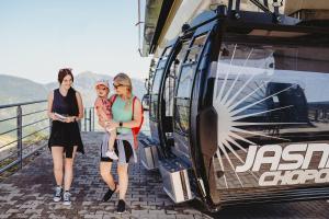 Zwei Frauen und ein Kind stehen neben einem Zug. in der Unterkunft Hotel Grand Jasná in Demänovská Dolina