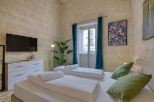 ein Schlafzimmer mit zwei Betten, einem Fernseher und einem Fenster in der Unterkunft Heart of Gozo - Modern Rooms in shared Apartment - Victoria D-Central opposite Duke Shopping Center in Victoria