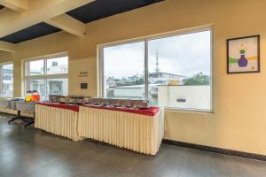 a large room with tables and large windows at Treebo Jaguar Comforts, 3 Kms From Mahatma Gandhi Park in Chikmagalūr