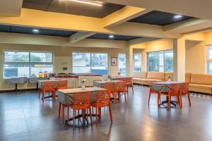 a dining room with tables and chairs and windows at Treebo Jaguar Comforts, 3 Kms From Mahatma Gandhi Park in Chikmagalūr