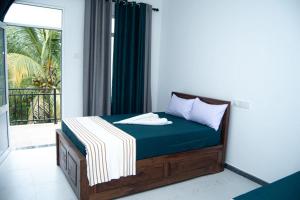 a bedroom with a bed and a balcony with a window at Rainforest White House in Deniyaya