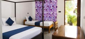 a bedroom with two beds and a bench in it at FS Hotel & villa in Arugam Bay