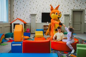 ein kleines Mädchen und ein Kind in einem Raum mit einem Maskottchen in der Unterkunft Hotel Grand Jasná in Demänovská Dolina