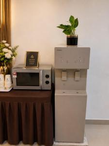 a microwave and a refrigerator next to a table with a plant at StarQ Hotel Bukit Bintang in Kuala Lumpur