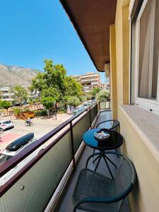 a balcony with two chairs and a table and a window at IRIS Apartment in Loutraki