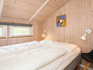 a bedroom with a white bed in a wooden wall at 4 star holiday home in Tarm in Tarm
