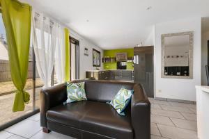 a living room with a leather couch and a kitchen at Maison La Plouhinecoise in Plouhinec