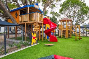 a playground with a tree house and a slide at Summer Set West in Somerset West