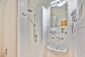 a white bathroom with a shower and a sink at Hotel Osrblie in Osrblie