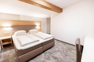 ヴァルヒゼーにあるDas Walchsee Resortの白いシーツと枕が置かれた大きなベッドのある寝室