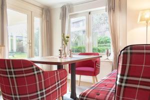a dining room with red chairs and a table and windows at Ferienwohnung Onkel Toms Hütte in Scharbeutz +14 photos