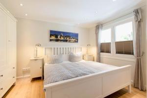a white bedroom with a white bed and two windows at Ferienwohnung Onkel Toms Hütte in Scharbeutz