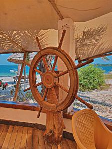 a wooden steering wheel on a deck with a beach at Triple A visitors in Kilindoni
