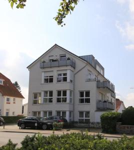 a white building with cars parked in front of it at Ferienwohnung Seestern in Timmendorfer Strand