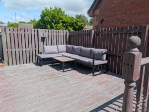 a couch on a wooden deck with a fence at The Yard Bungalow in Sanquhar