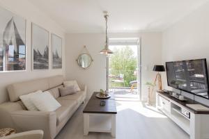 a white living room with a couch and a tv at Ferienwohnung Ankommen in Timmendorfer Strand