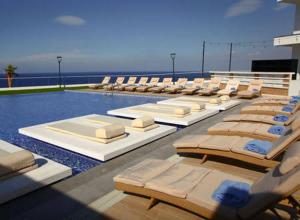 a row of lounge chairs sitting next to a swimming pool at Luxury Sea & Pool View Apt at Caesar Cliff Esentepe in Perivolia tou Trikomou