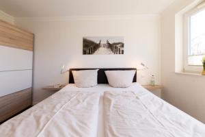 a bedroom with a large bed with white sheets at Ferienwohnung Dünenhäuser App. A2 in Scharbeutz