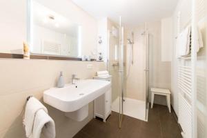 a white bathroom with a sink and a shower at Ferienwohnung Dünenhäuser App. A2 in Scharbeutz +22 photos