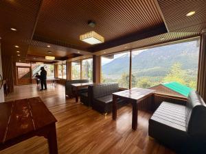 a living room with couches and tables and a large window at Hotel Naina Rockland , Manali in Vashisht