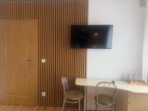 a room with a table and two chairs and a television on the wall at Hotel Mimoza in Libusza