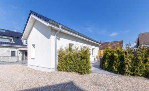 a white house with bushes in front of it at Ferienwohnung 3 Haus Meeresrauschen - Bungalow in Haffkrug