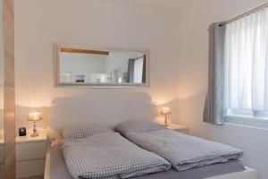 a bed with two pillows in a room with a mirror at Ferienwohnung 3 Haus Meeresrauschen - Bungalow in Haffkrug