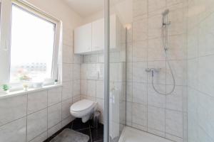 a white bathroom with a shower and a toilet at Ferienwohnung 3 Haus Meeresrauschen - Bungalow in Haffkrug +13 photos