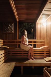 Eine Frau sitzt auf einer Bank in einer Sauna in der Unterkunft Hotel Ostredok in Demänovská Dolina