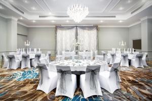 a ballroom with white tables and chairs and a chandelier at Leonardo Royal Hotel Brighton Waterfront in Brighton & Hove +37 photos