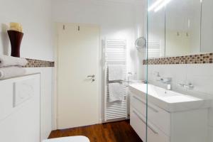 a white bathroom with a sink and a shower at Ferienwohnung Ostseestübchen in Scharbeutz +18 photos